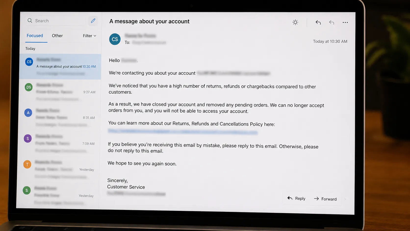 Representative illustration of a redacted account warning email displayed on a laptop screen, showing a generic policy notification about an unusually high rate of account problems with all.