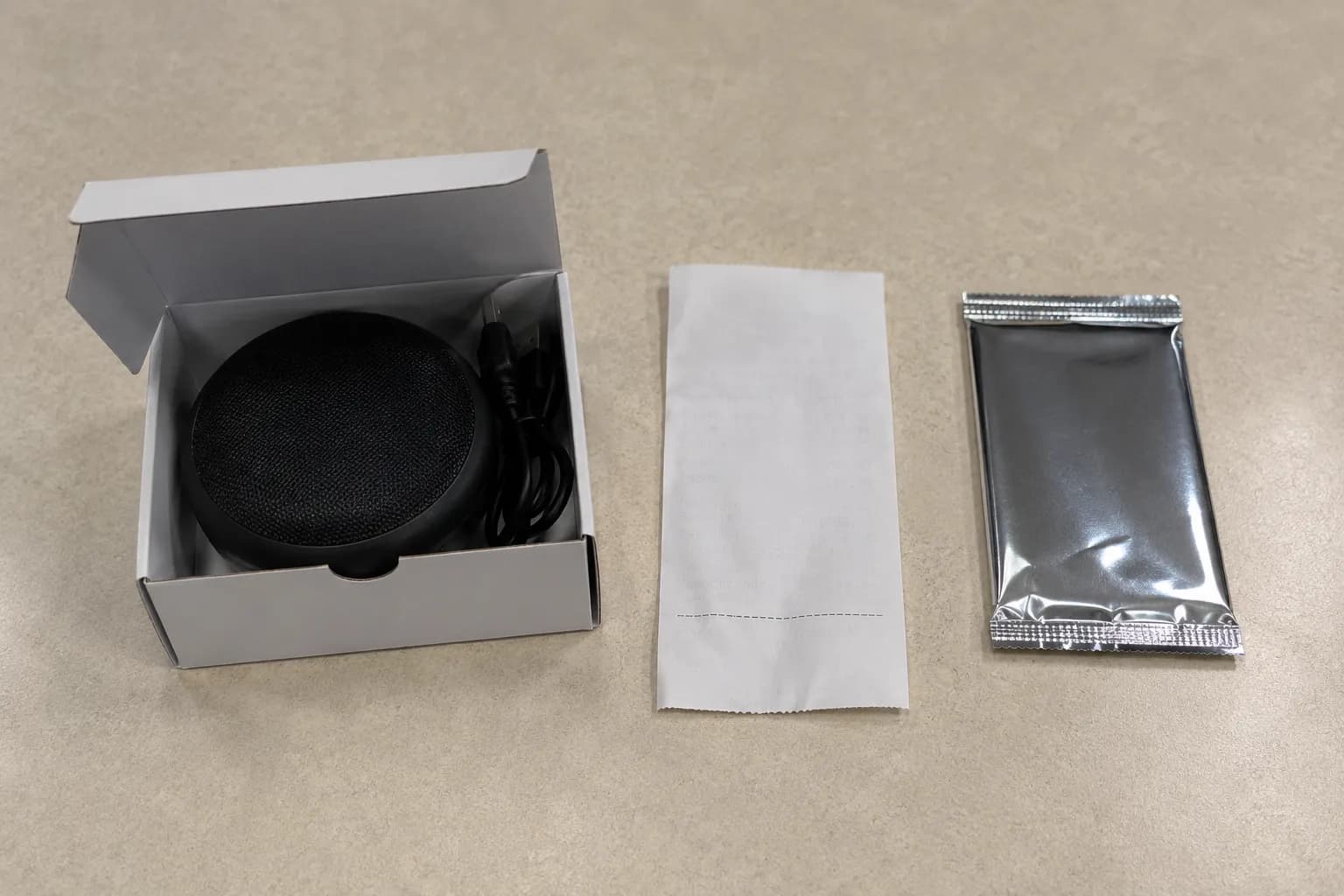 Opened electronics box with a small speaker beside a sealed foil card pack and receipt, illustrating two refused return items.