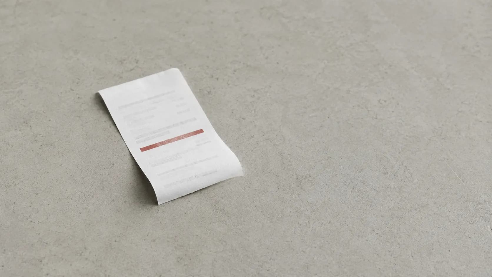 A printed return denial receipt with a highlighted reason code lying on a grey counter surface, representing a declined product return at checkout.