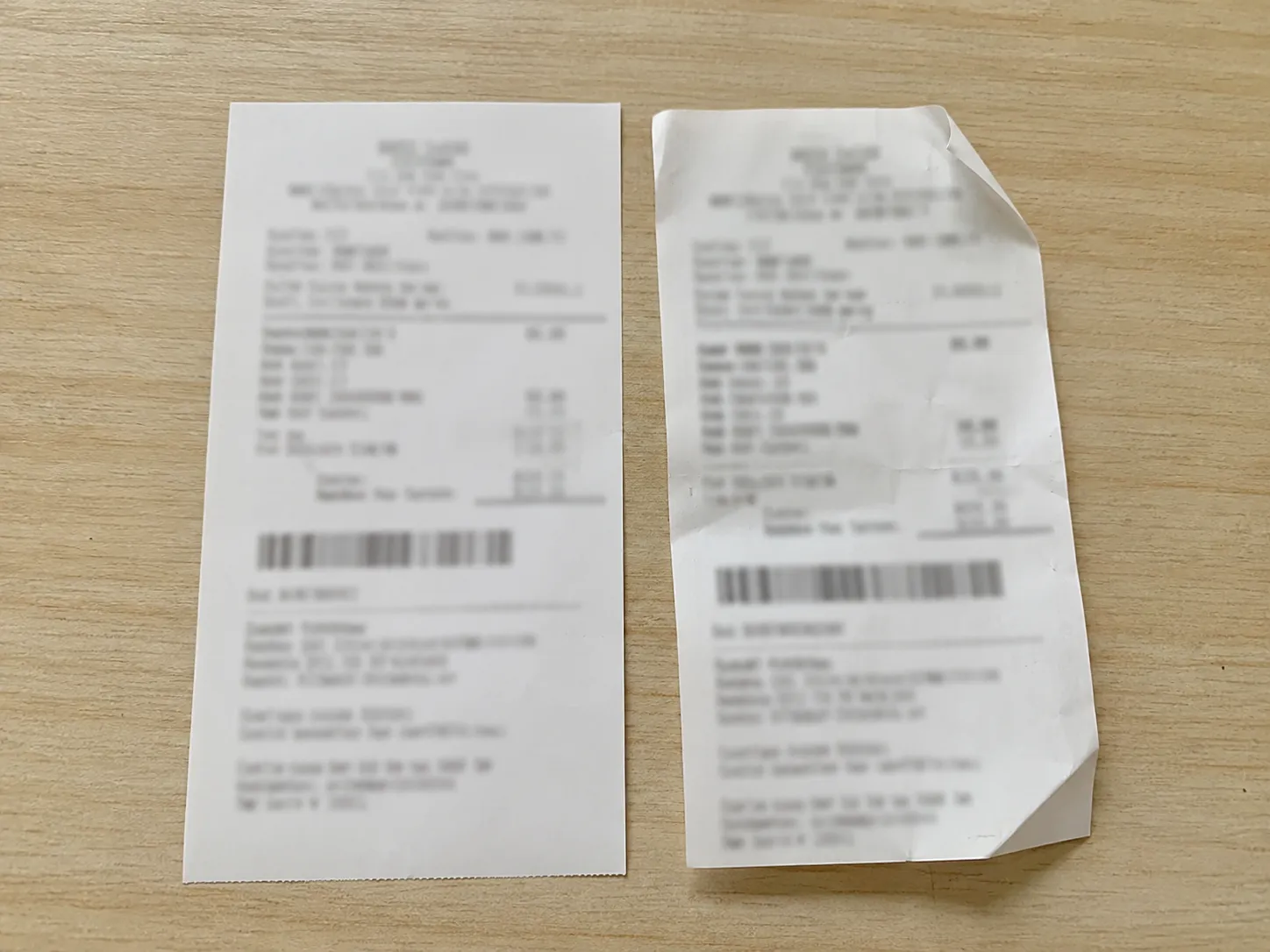 Two anonymized retail receipts side by side on a light wood table, illustrating an accepted TV return and a refused phone return with dates visible and personal details redacted.