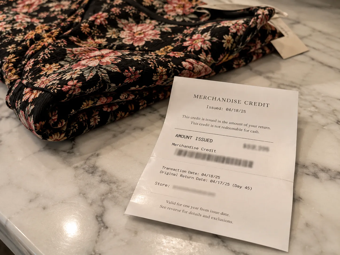 Anthropologie merchandise-credit slip issued for a day-45 return, resting beside a folded dress.