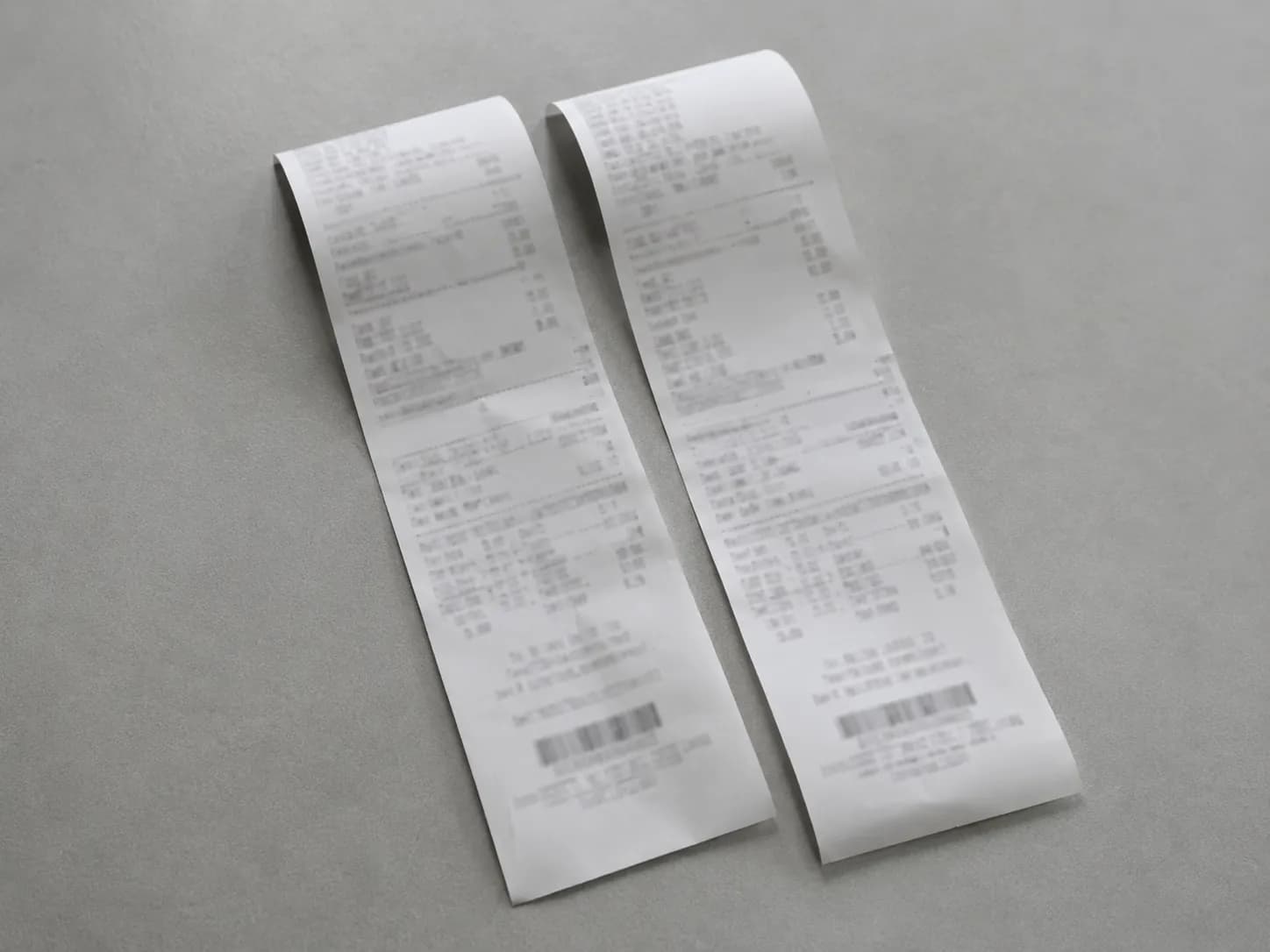 Representative illustration of two thermal retail receipts placed side by side on a gray surface, symbolizing documentation for the same opened diaper pack that was refused at one store and successful