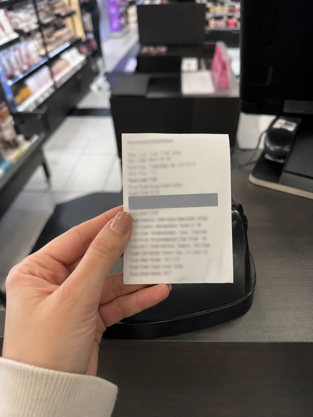 Representative illustration of a hand holding a printed retail return-decline notice near a checkout counter with identifying details redacted and a blurred store background.