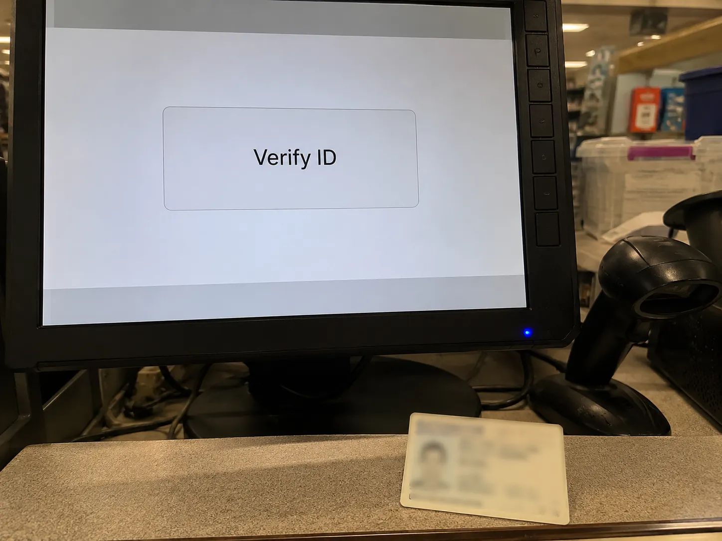 Over-the-shoulder view of a retail service desk POS screen displaying “Verify ID,” with a blurred ID card and barcode scanner during a no-receipt return transaction.